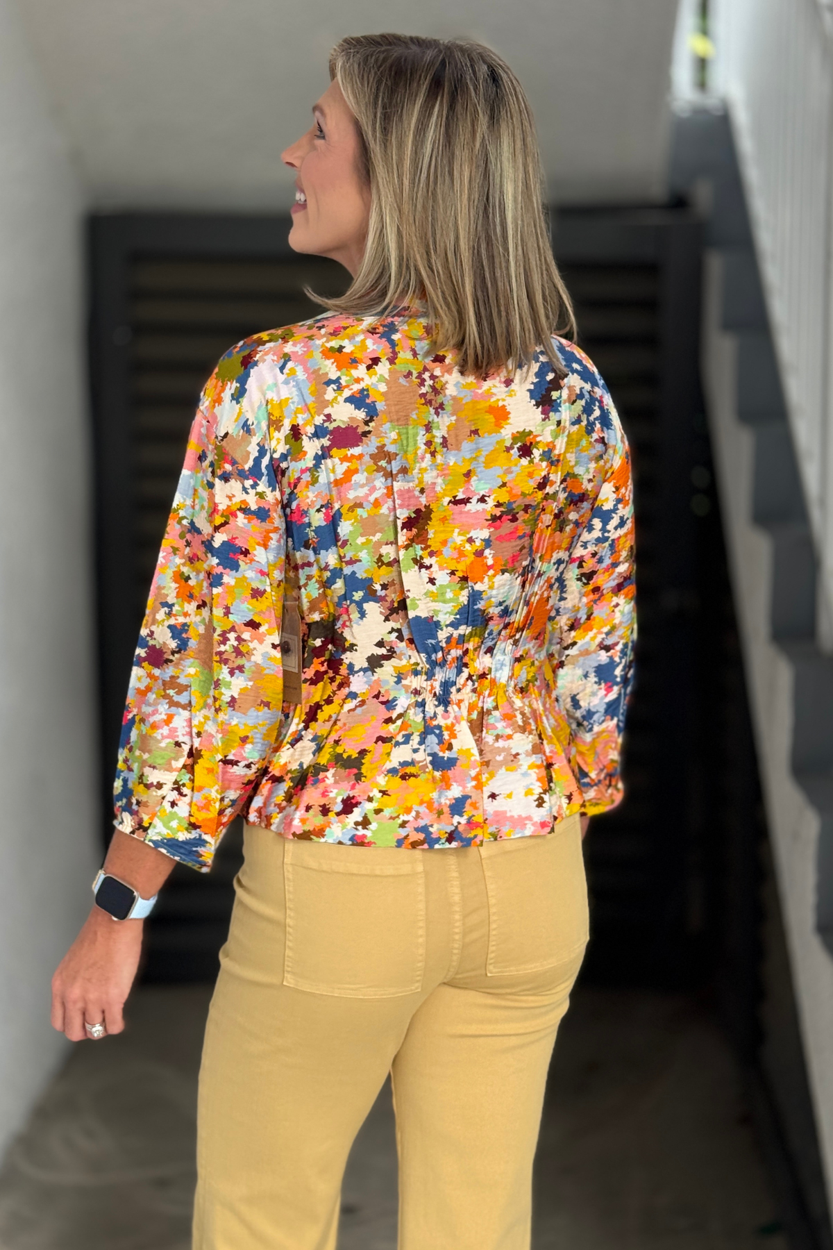 Back view of the TRU LUXE Multi Printed Top highlighting the vibrant print and gathered waist design.