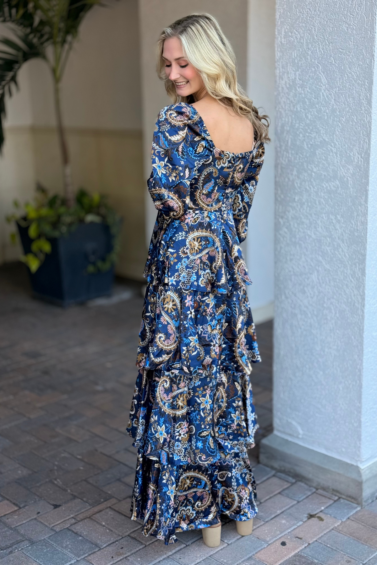Woman wearing a blue floral dress standing in an outdoor setting.