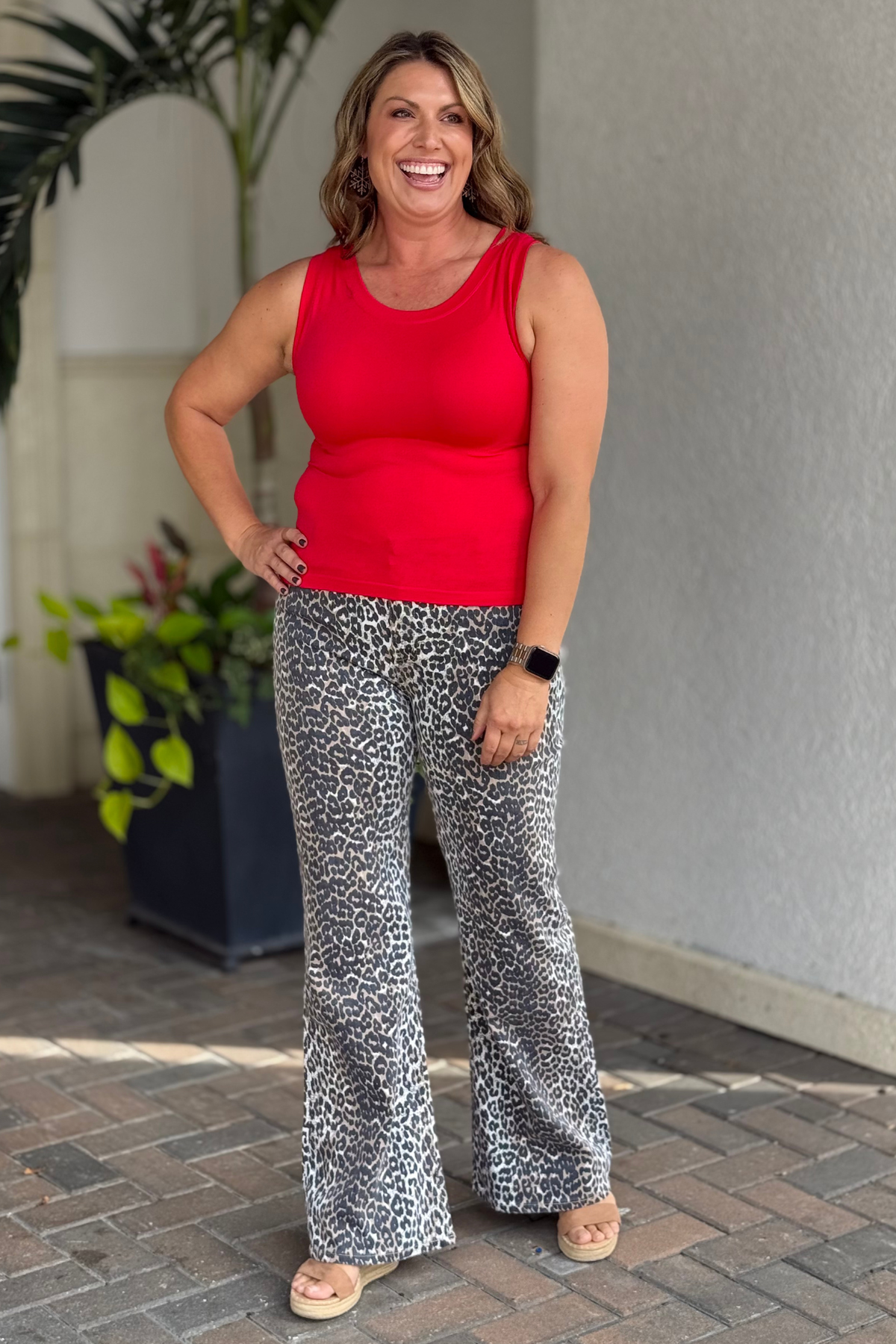 Woman wearing Tractr leopard print bootcut pants with red tank top and sandals