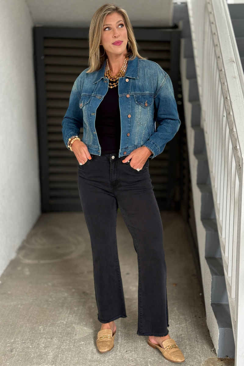 Front view of blue cropped denim jacket with button-front closure and shirt collar.