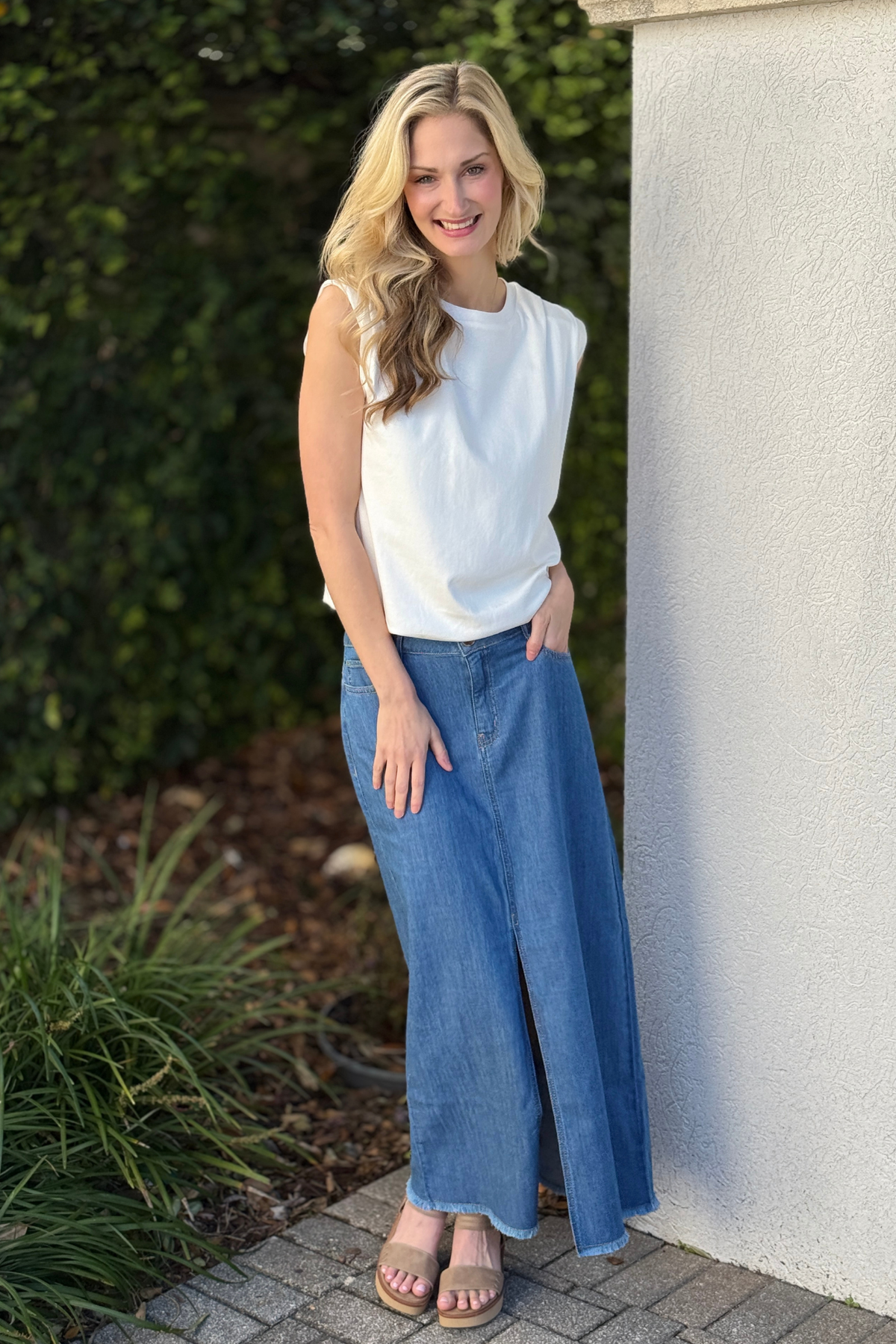 Woman wearing Tribal fjord blue full length denim skirt with front slit styled with sleeveless white top