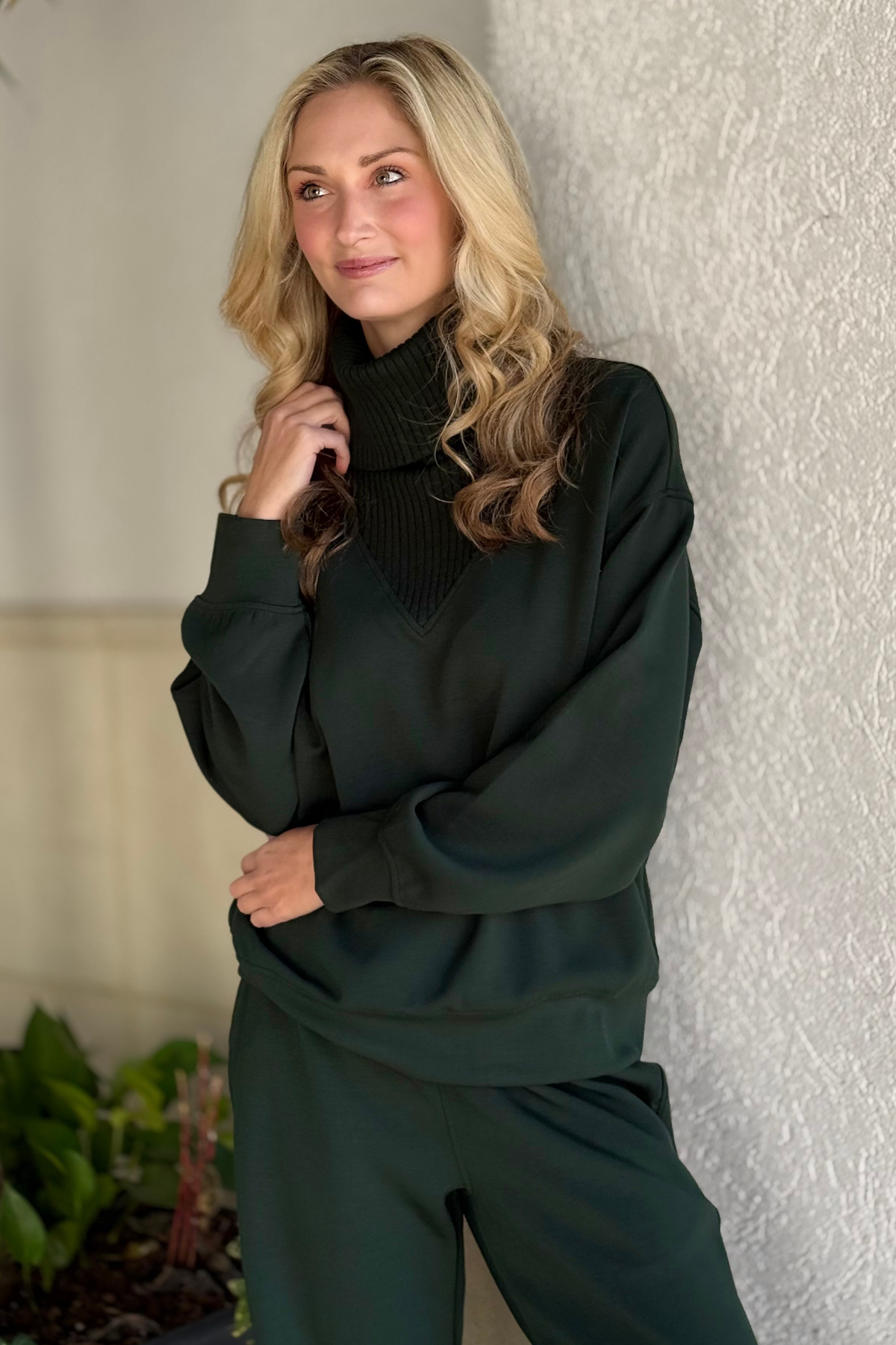 Woman wearing the full Regency Green Modal Scuba Luxe Set with matching V-turtleneck top and joggers.