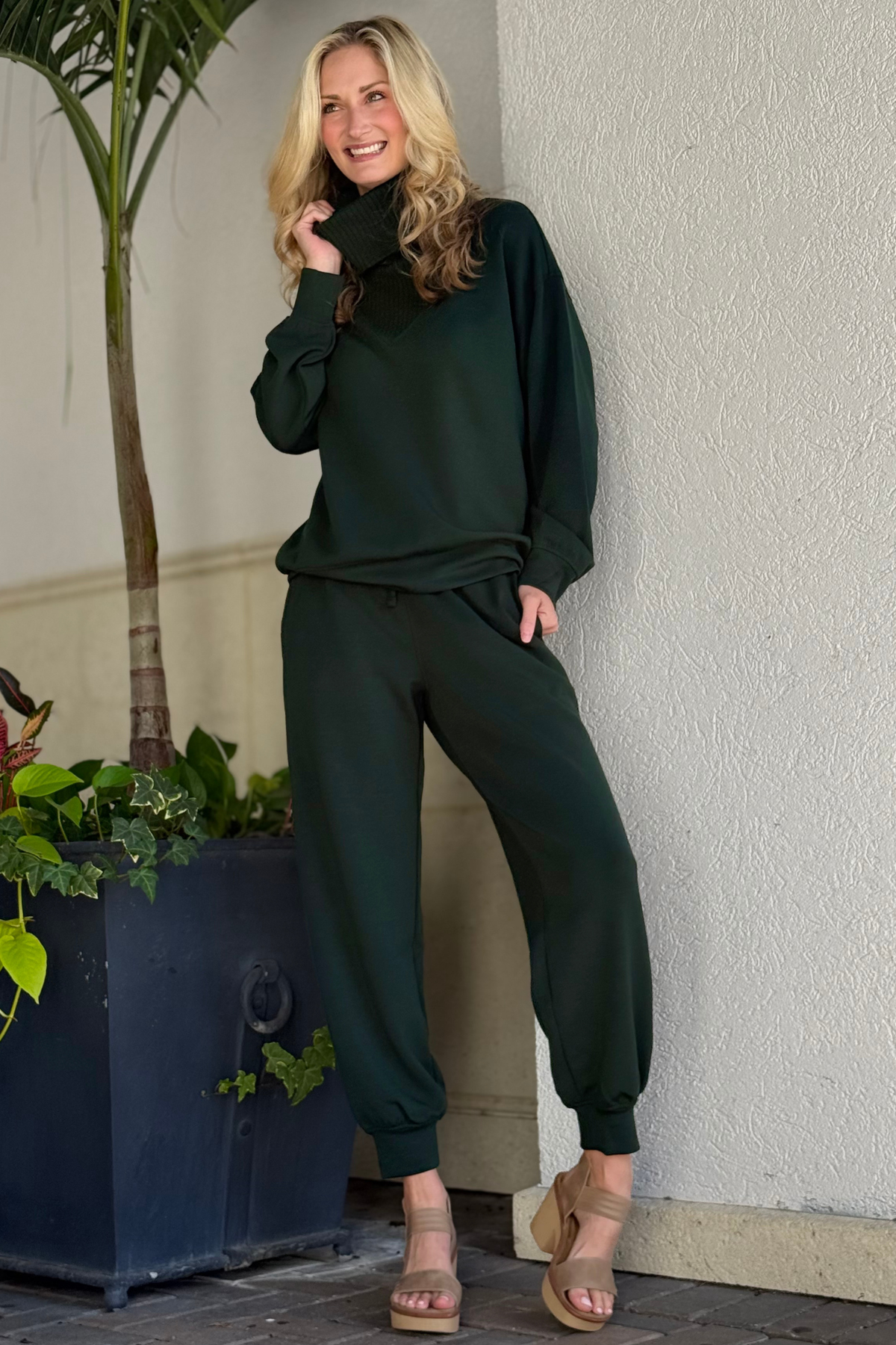 Model wearing the Regency Green Modal Scuba Luxe V-Turtleneck featuring a ribbed neckline and relaxed fit.