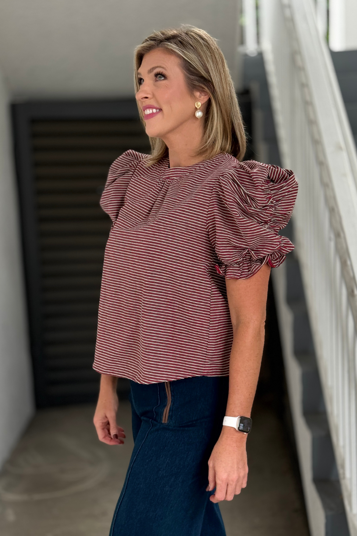 Side view of Burgundy Stripe Ruched Puff Sleeve Top styled with denim