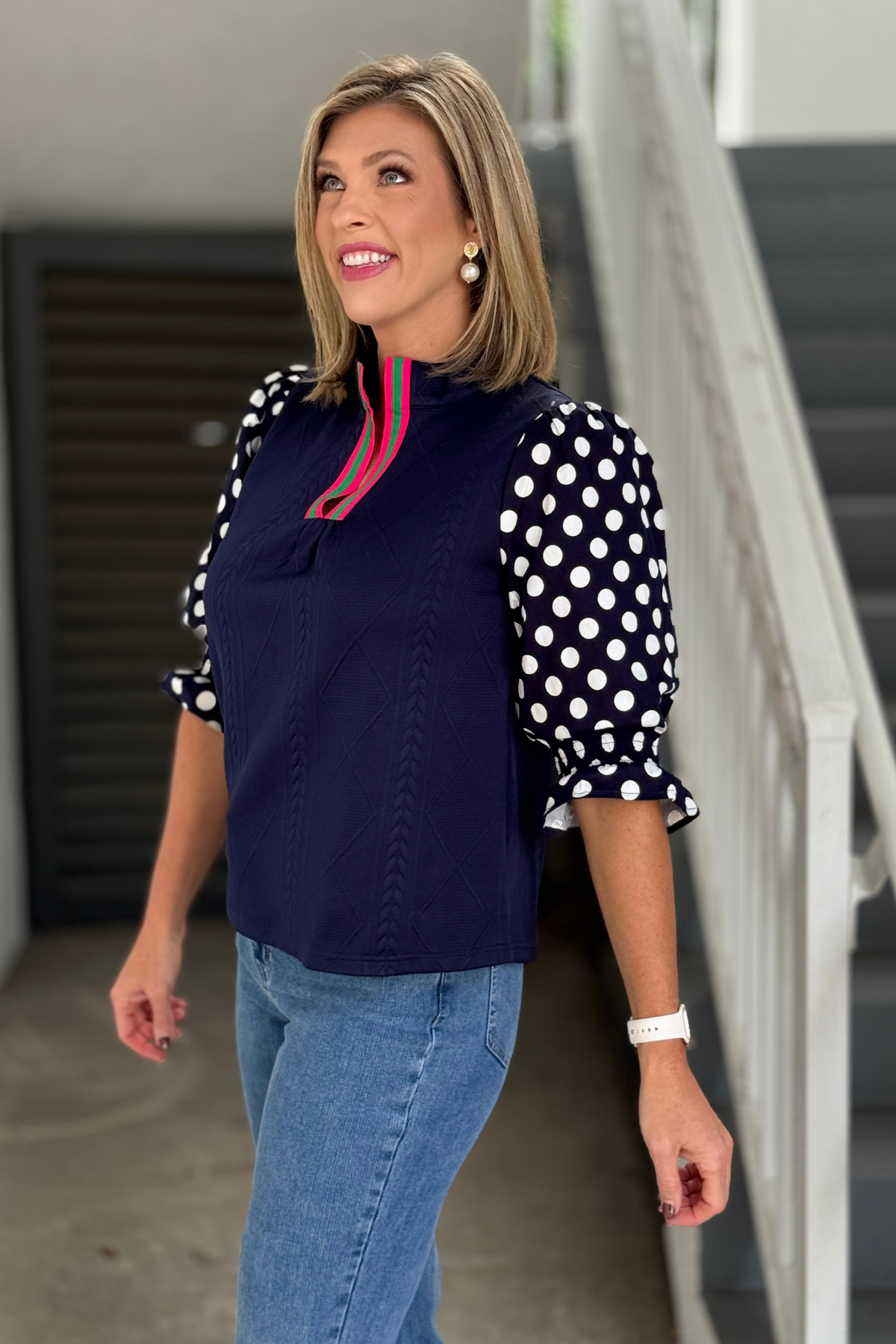 Side view of navy polka dot contrast sleeve boutique top