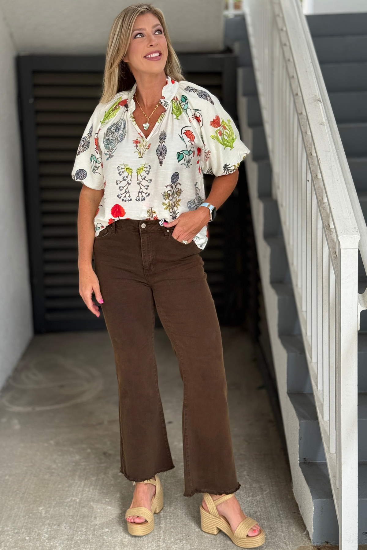 Woman wearing The Essential Wide Leg Jeans in Espresso with a high-rise fit, wide leg silhouette, raw frayed hem, and stretch denim paired with a printed blouse.