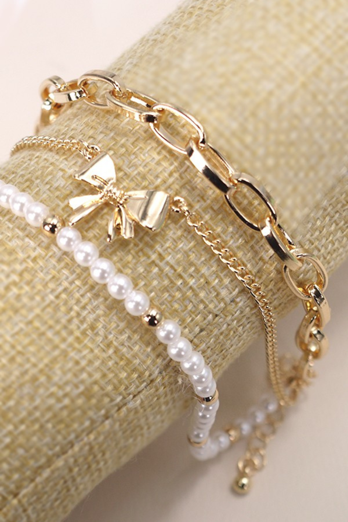 gold bow pearl bracelet trio set on linen background