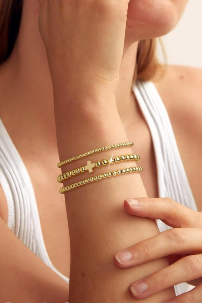 layered gold beaded bracelet with cross charm