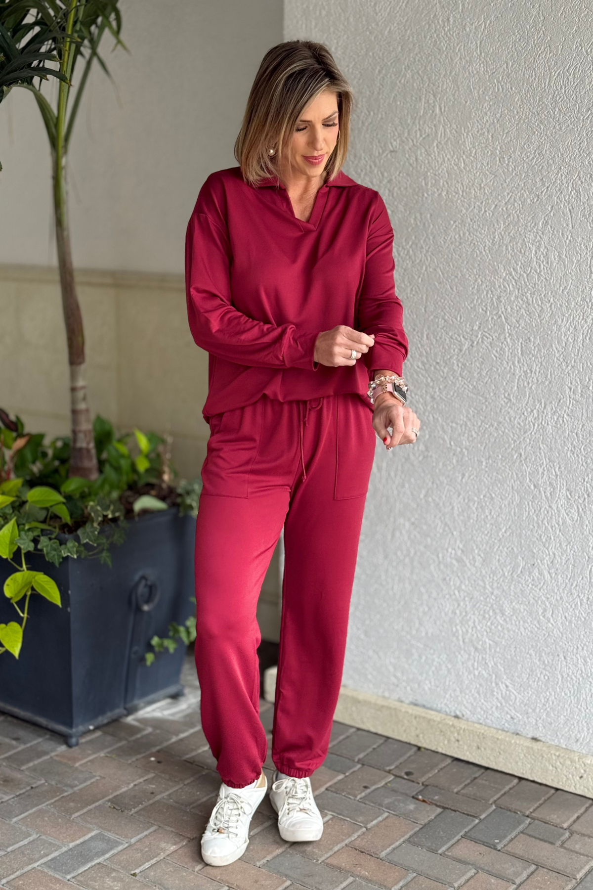 Woman wearing cabernet french terry two-piece lounge set with collared top and jogger pants.