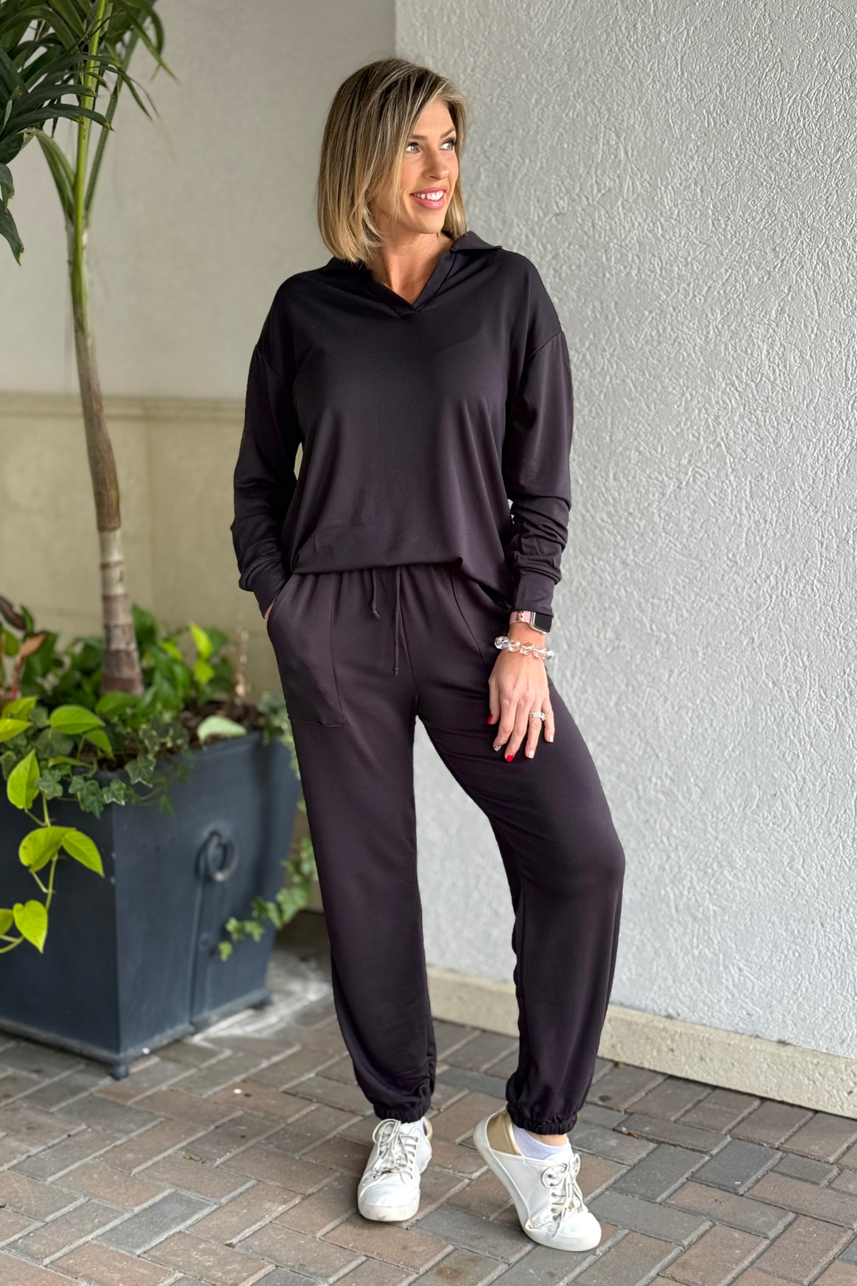Woman wearing charcoal black french terry two-piece lounge set with collared top and jogger pants.