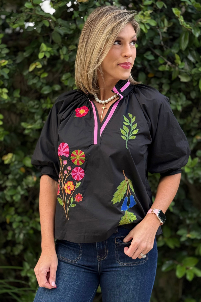 Close-up of floral embroidery detail on The Valencia Embroidered Blouse in black with contrast pink neckline.