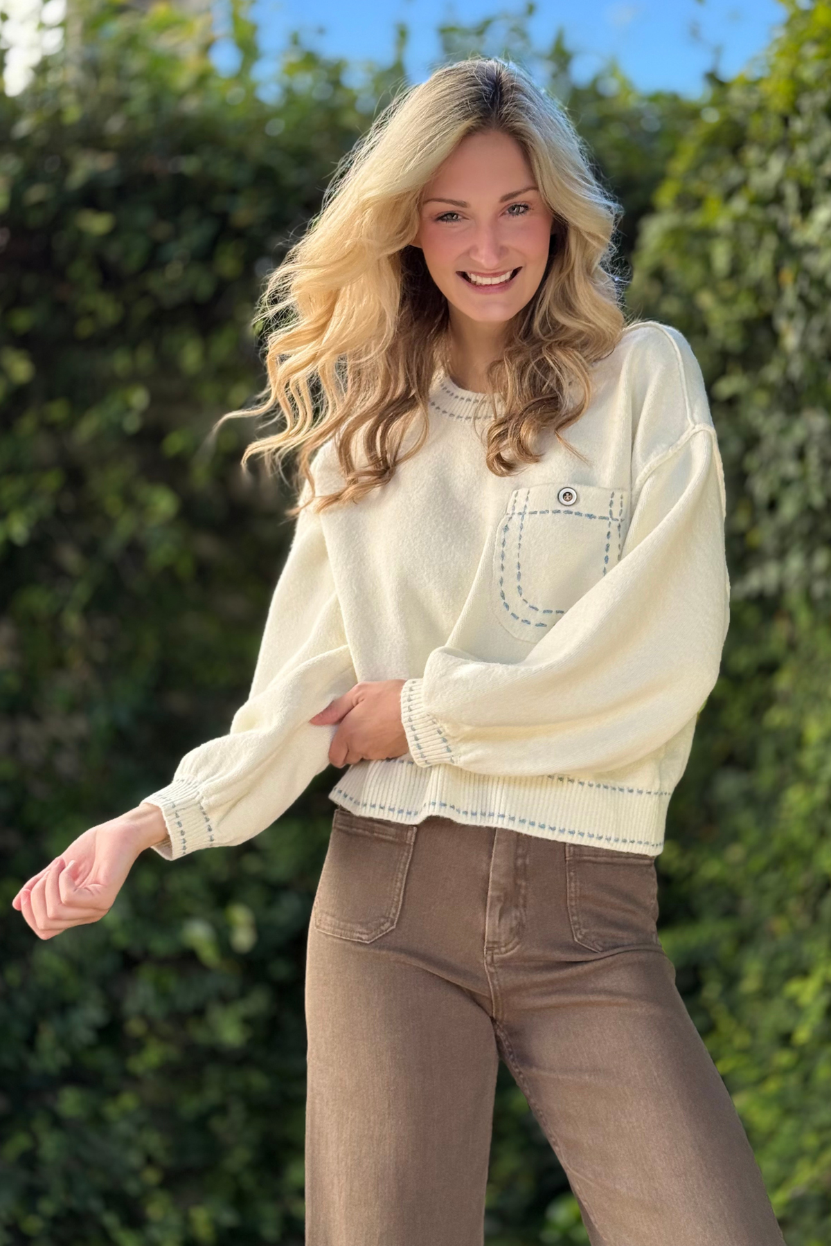 Model wearing Enzo Contrast Stitch Sweater Top in cream with contrast stitching and front pocket