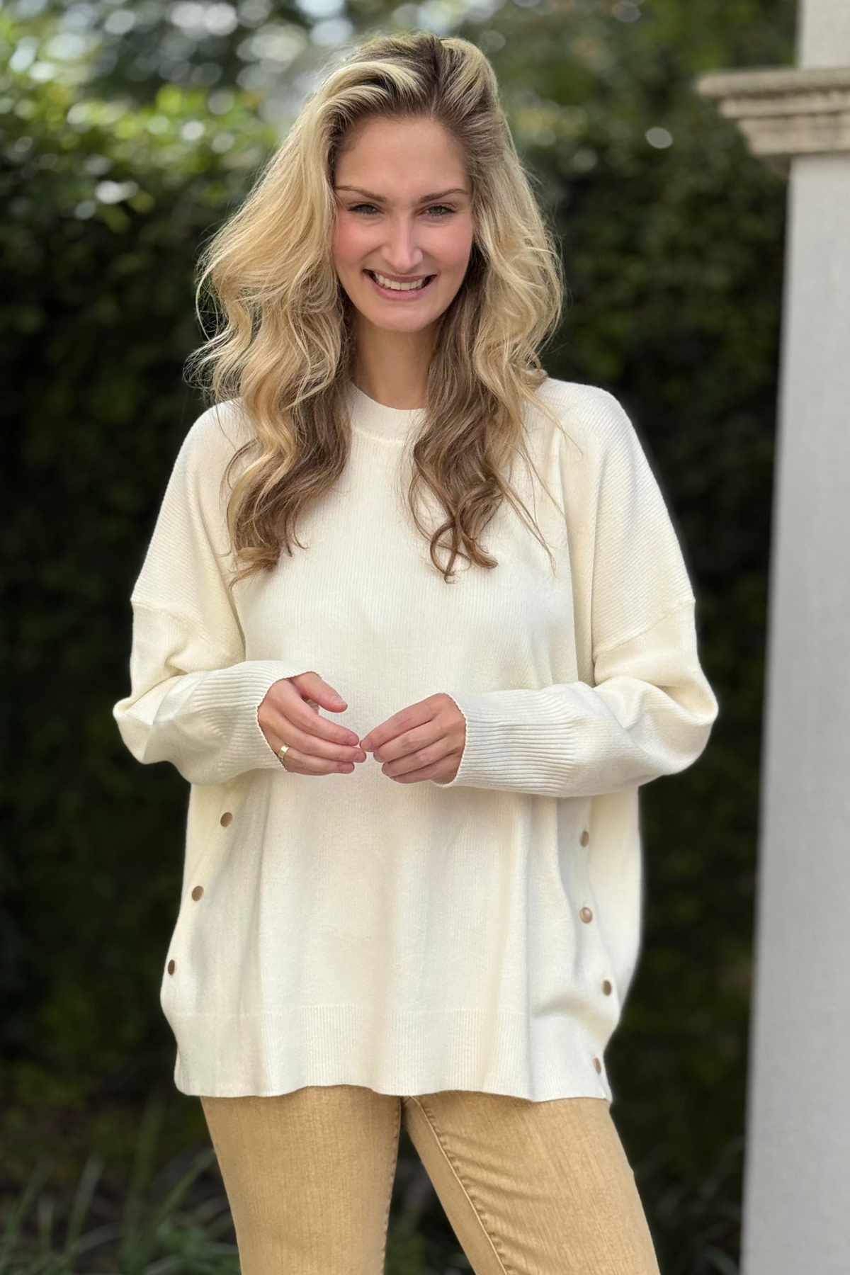 Woman wearing Noralee Button Sweater in ivory – soft knit sweater with brass button placket detail.