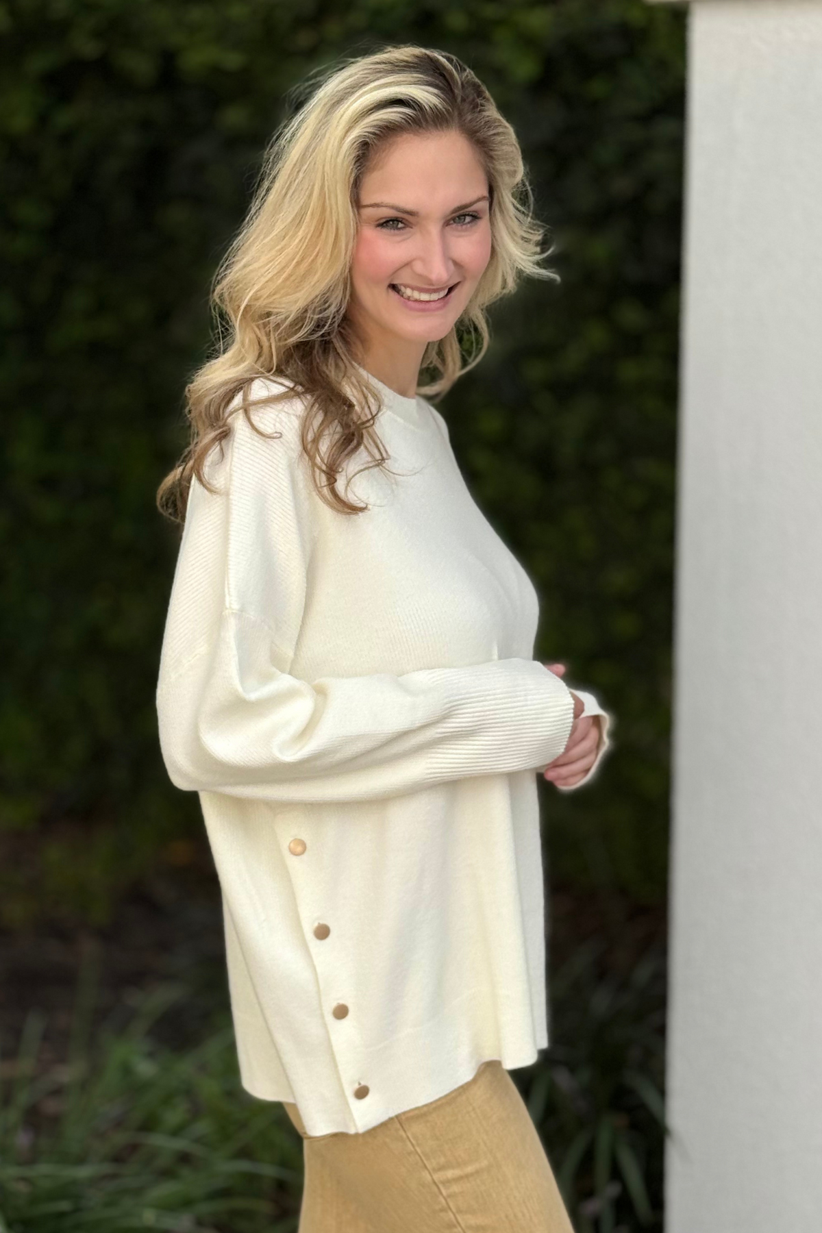 Woman wearing Noralee Button Sweater in ivory – soft knit sweater with brass button placket detail.