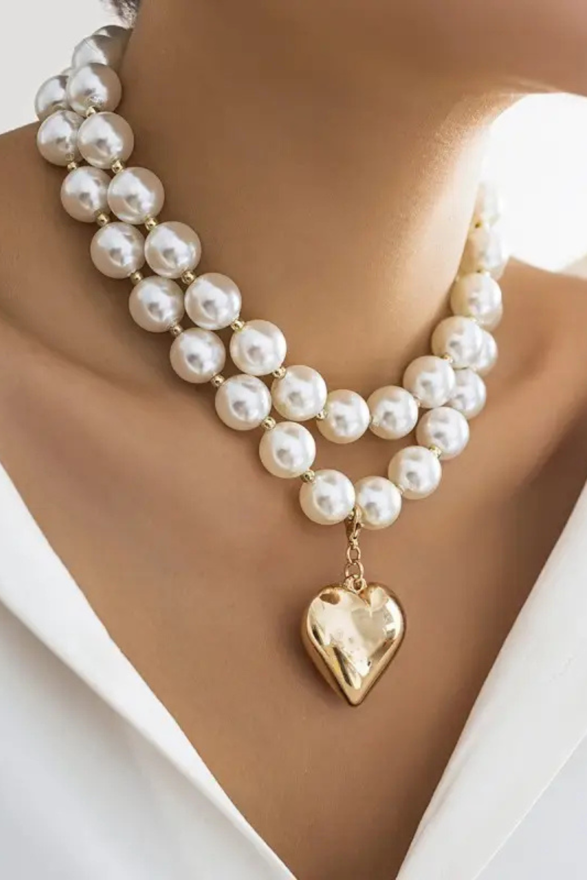layered pearl necklace with gold heart charm on model