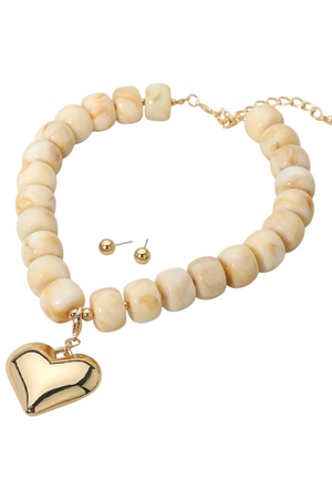 Chunky neutral marbled bead necklace with gold puffy heart pendant and matching stud earrings.