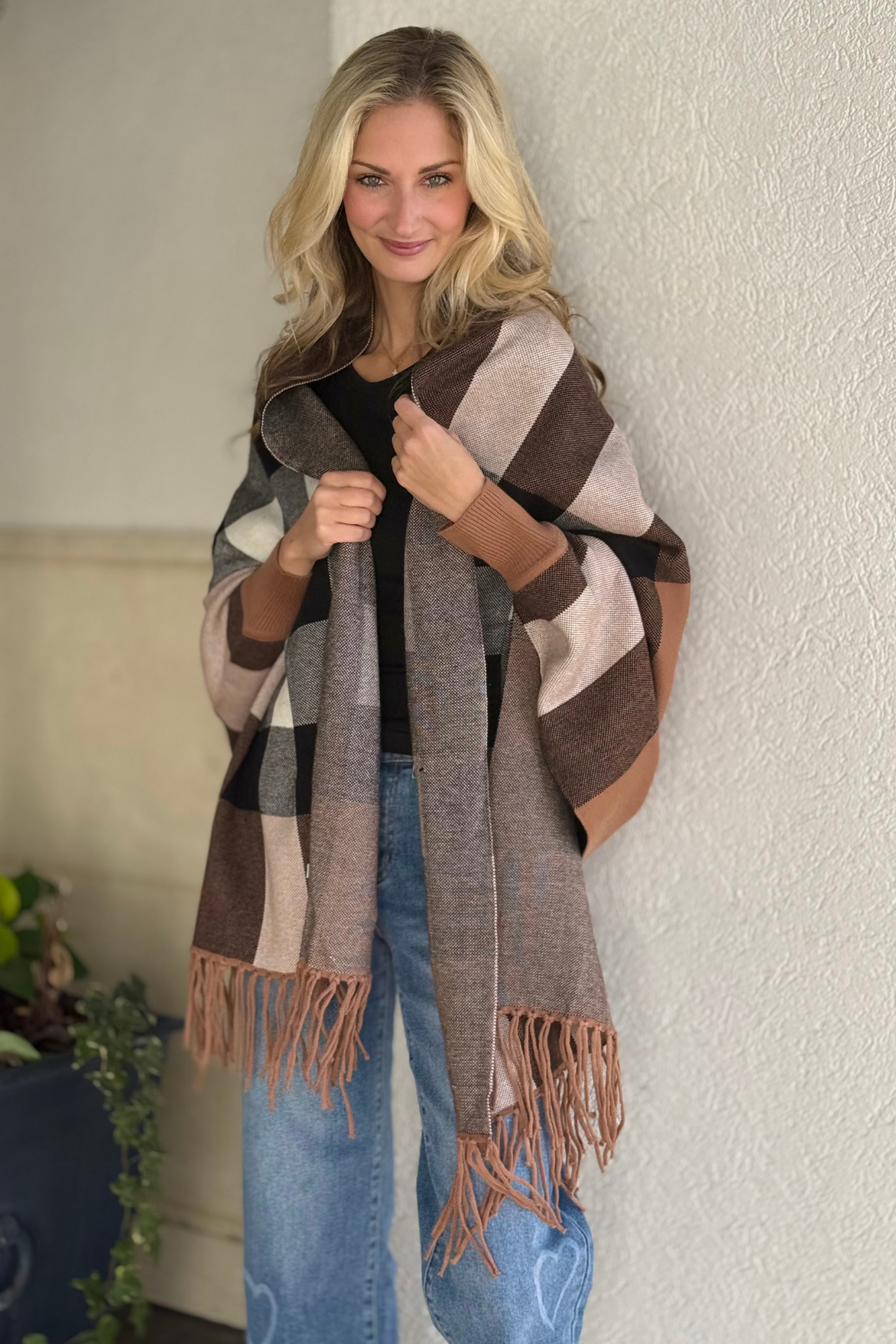 Woman wearing beige checkered fringe shawl poncho