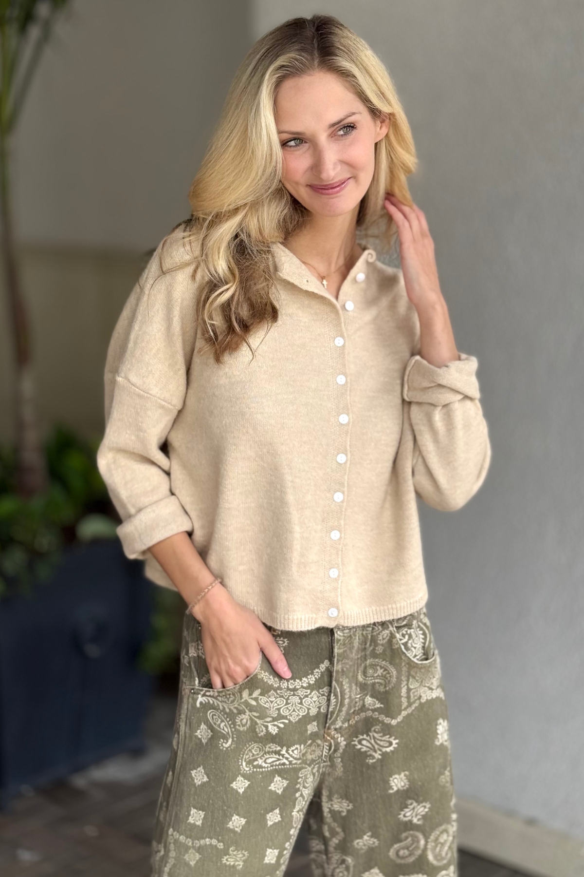 Woman wearing a sand-colored button front cardigan with long sleeves and a relaxed fit.